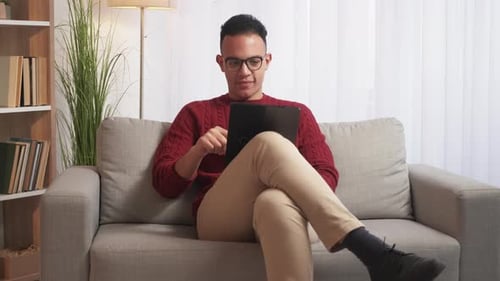 Man using Tablet on Couch Indoors
