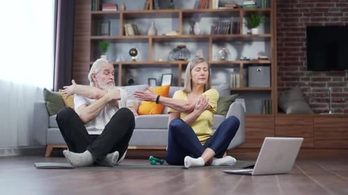 Senior Couple Stretching Together in Living Room