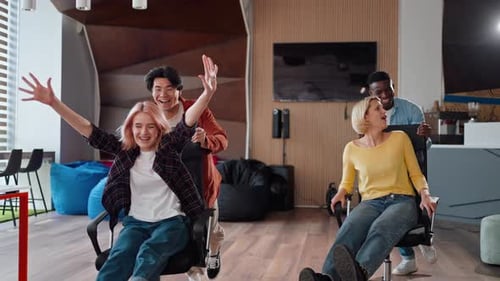 Multiethnic Office Workers in Casual Clothes Playing on Chairs in Hallway People Office Routine