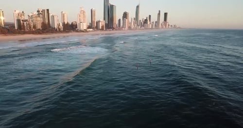Drone aerial pan up with stand up paddle boarders on ocean during sunrise