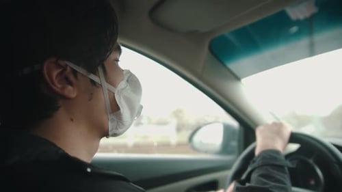 Young Adult Driving a Car Wearing a Protective Mask