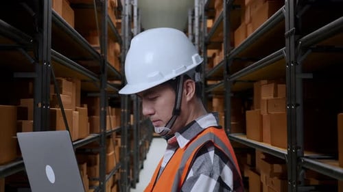 Nahaufnahme eines asiatischen männlichen Ingenieurs, der im Lagerhaus an einem Laptop arbeitet