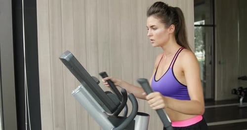 Sporty Woman on Elliptical Trainer in the Gym