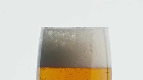 Glass of beer with foamy head close up
