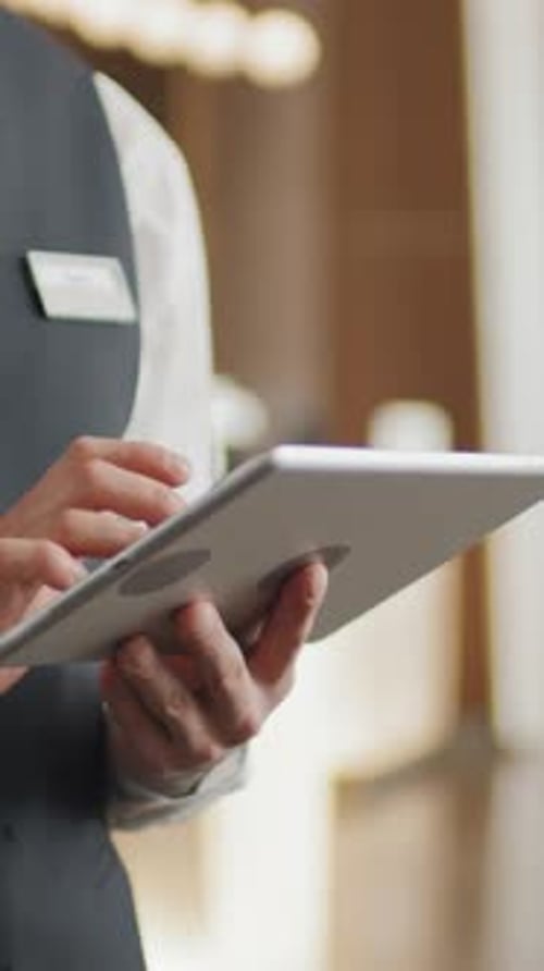 Unrecognizable Hotel Concierge Using Digital Tablet in Lobby
