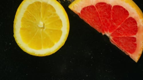 Bright Citrus Fruits Splashing into Liquid