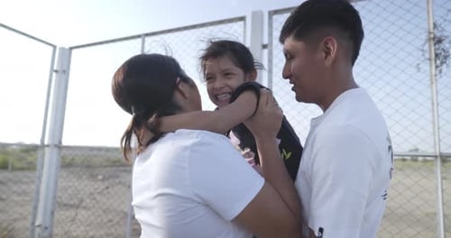 Very happy young family composed of father, mother and daughter, hug and smile in the garden of thei