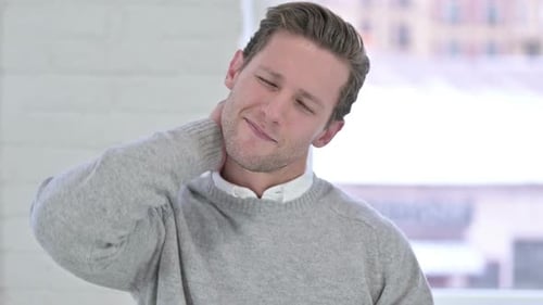 Young Adult Rubbing Neck in Pain Indoors