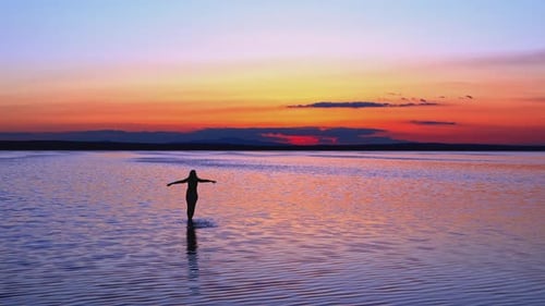 Silhouette Standing in Water at Colorful Sunset