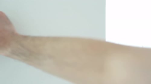 Hand Extending Yellow Measuring Tape Against White Wall