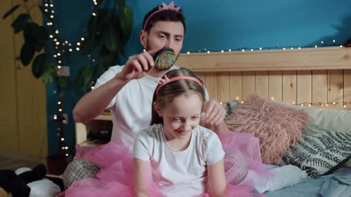 Bearded Man Brushing Child's Hair in Tutu and Crown