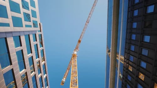 Walk Down the Street Under a Huge Tower Crane Construction in Downtown of the Big City Low Angle