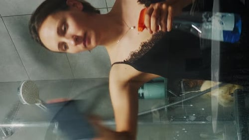 Woman with detergent and wipe in hands cleaning dirty shower glass. Vertical video