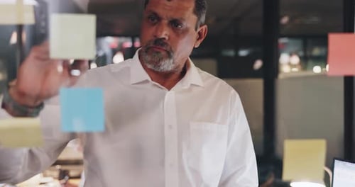 Thoughtful Man Planning Project at Sticky Note Wall
