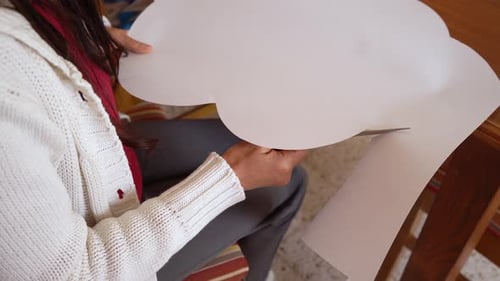 Woman Cutting White Paper with Scissors Indoors