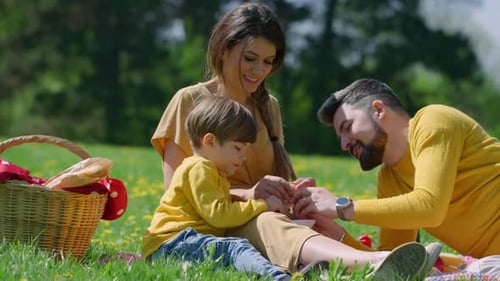 Happy Family Enjoying Picnic in Green Meadow