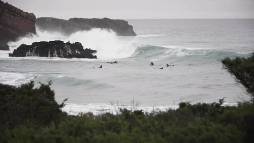 Surfers Riding Waves on a Rocky Coastline