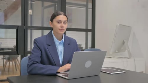 Woman Typing and Smiling at Laptop in Office