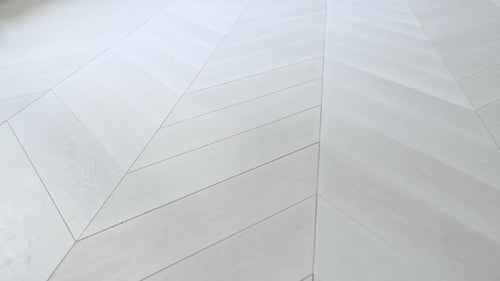 Vue panoramique sur un parquet en bois à chevrons avec son motif décoratif répété dans un intérieur