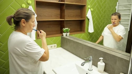 Woman Brushing Teeth in Modern Bathroom Mirror