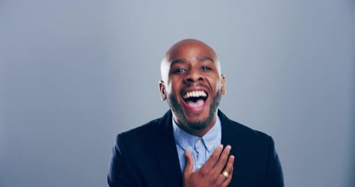 4k video footage of a young man laughing against a grey studio background