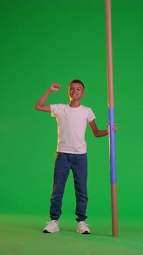 A Schoolboy Holds a Blue Stick at the Green Screen