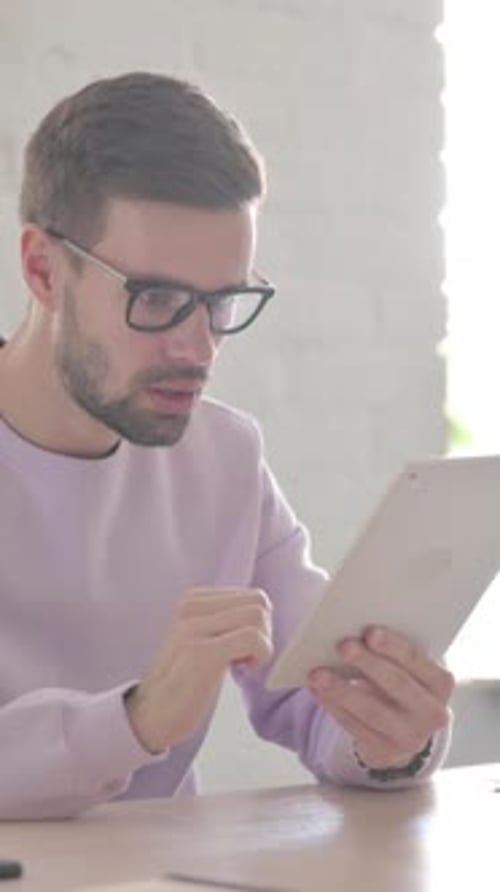 Young Man having Loss on Tablet in Office, Vertical Video