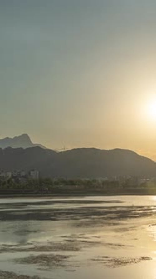 Time laps on the riverbank, sunset over the mountain Vertical video.