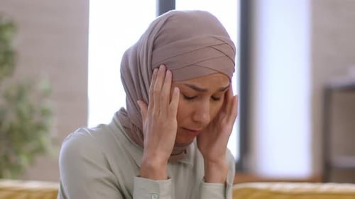 Sad Woman Massaging Temples Indoors