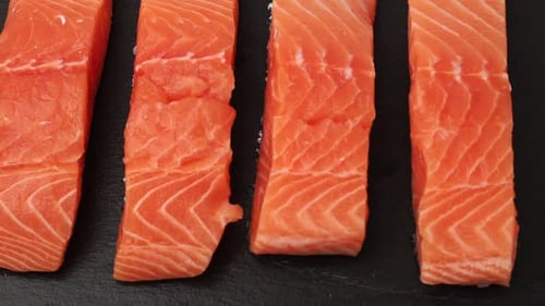Raw Salmon Fillets on Dark Surface
