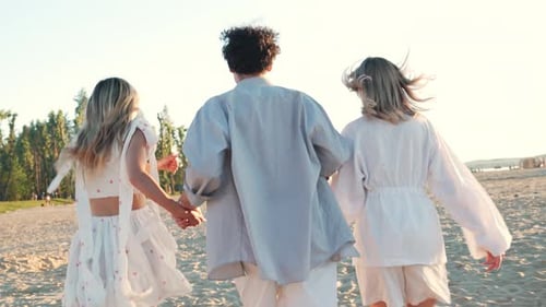 Man and two girls run at the beach
