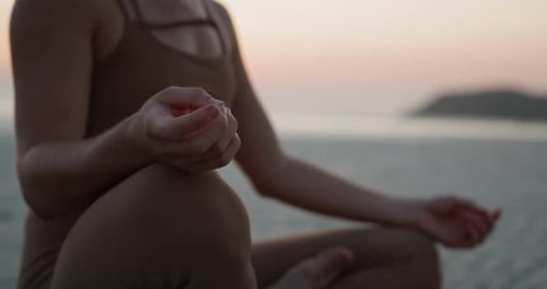 Crop View of Young Woman Meditates in Padmasana Pose on Dusk Morning Sea Beach