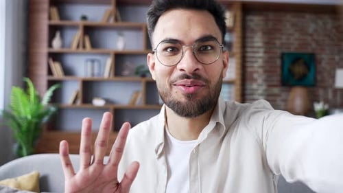 Smiling Man Waving Hello in Modern Living Room