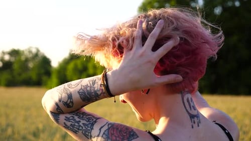 Young Punk Girl with Pink Hair Looking at Beautiful Evening Sunset at Wheat Green Field Happy Female