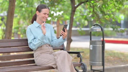 Woman Uses Smartphone for Video Call in Park