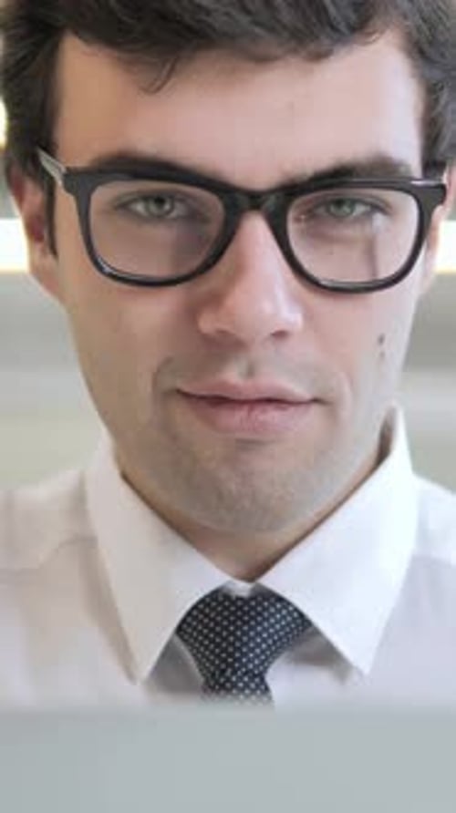 Smiling Young Man Wearing Glasses and Tie at Work