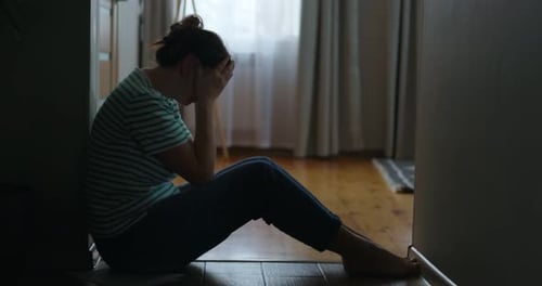 Woman Sits on Floor With Face in Hands