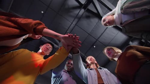 A View From Below of Young Motley People Holding Hands Demonstrating Unity Team