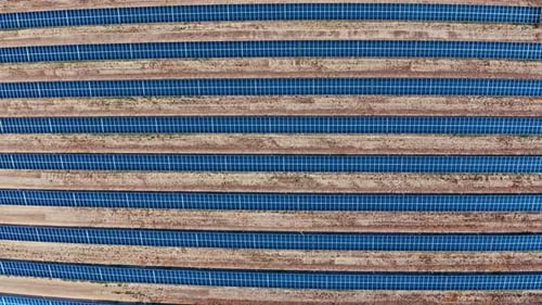 Eine Luftaufnahme von oben nach unten von Reihen von Sonnenkollektoren in einem großen Solarpark. Die klaren, symmetrischen Linien o