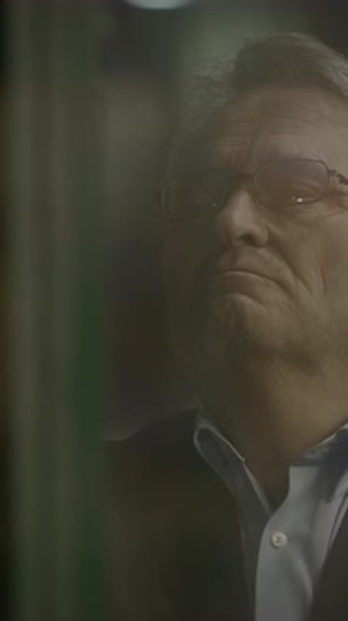 A Thoughtful Man Stands Behind Glass Bathed in Soft Light Creating an Evocative Atmosphere