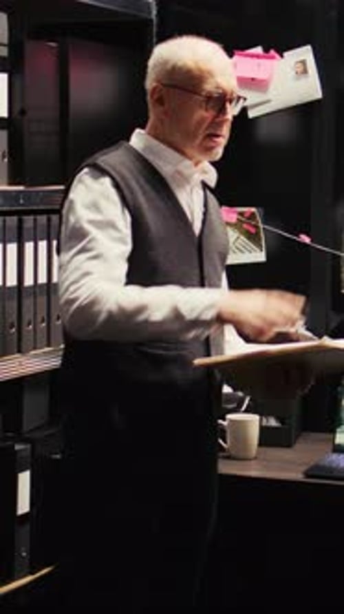 Man Reviews Documents in Dark Workspace