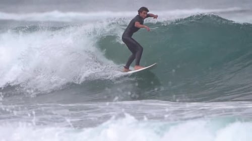 Surfer ride waves in slow motion at Las Canteras beach in Las Palmas de Gran Canaria, Spain.