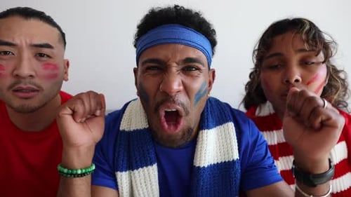 Excited Sports Fans Cheer with Face Paint and Scarves