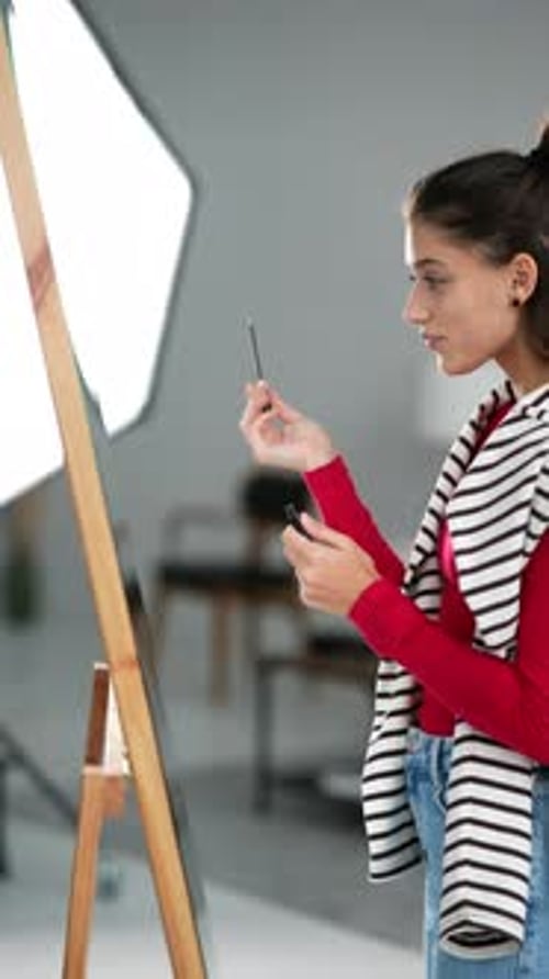 Young Woman Applying Makeup in Studio Setting