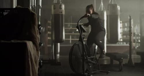 Sporty Woman Training on Air Bike in Gymnasium