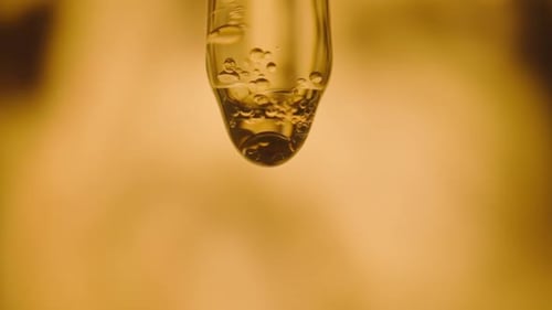 Liquid Droplets Falling from Glass Pipette Close-up