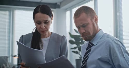 Two Employees in Modern Office Study Papers and Documents Brainstorm Strategy