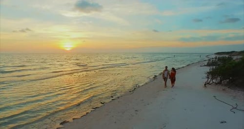 Young attractive couple walks on a beach during sunset