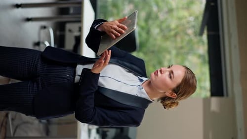 Vertical Video in Modern Office with a Large Window a Beautiful Female Worker Stands in a Blue Suit