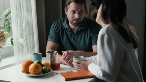 Couple Engaged in a Discussion at Cozy Table Setting Man and Woman Husband and Wife Discussing Plans